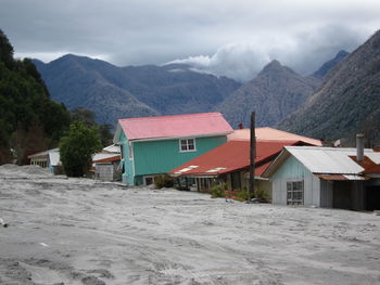 Houses on snowcapped mountain against sky