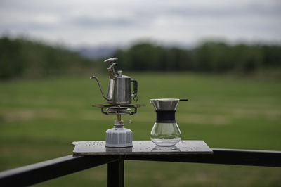 Close-up of faucet on field by railing