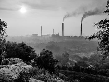 Smoke emitting from factory against sky