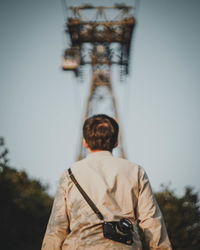 Rear view of man standing against overhead cable car