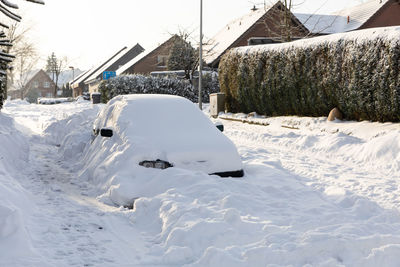 Snow covered houses on field by building