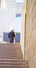 Rear view of woman standing on staircase against building