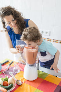 Woman preparing food while standing with son