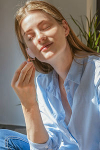 A beautiful girl does a facial massage with a roller at home in front of a mirror. facial skin care.