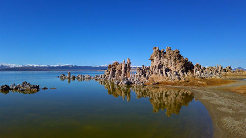 Rock formation in water against clear blue sky