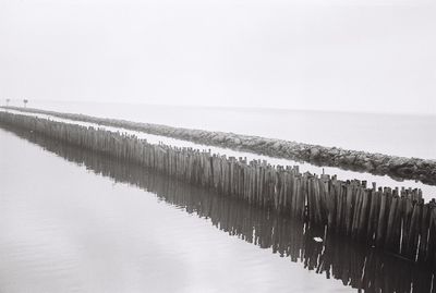 Wooden posts on beach against clear sky