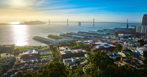 High angle view of townscape by sea against sky during sunset