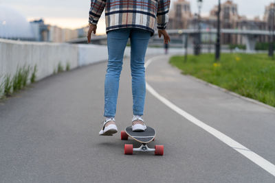 Female surfing city street on skateboard outdoors. mixed race african casual woman riding longboard