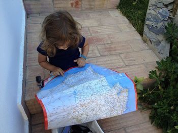 High angle view of girl with map sitting on steps
