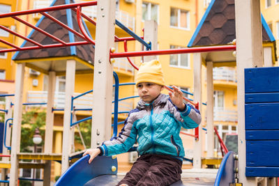 Full length of happy girl standing on slide in playground