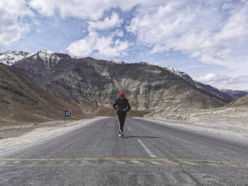 Rear view of man riding motorcycle on road against sky