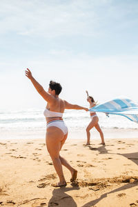 Friends enjoying at beach against sky