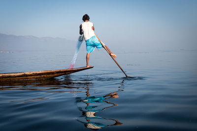 Man fishing net in water against sky
