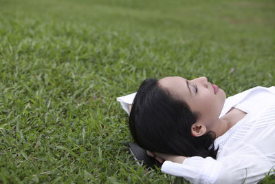 Woman lying on grassy field at park