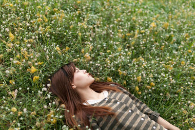 High angle view of carefree young woman lying down on grassy field