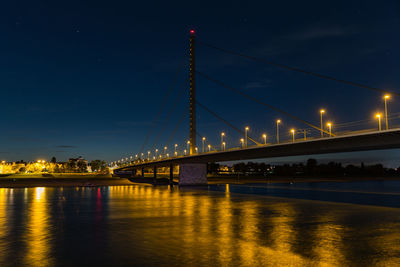Illuminated bridge at night against sky over river rhein