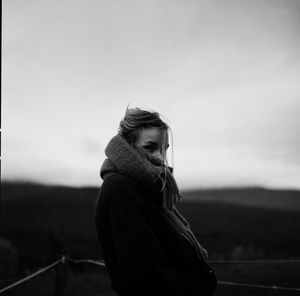 Side view of young woman standing against sky