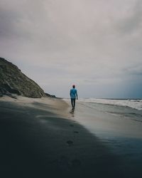 Rear view of man walking on land against sky