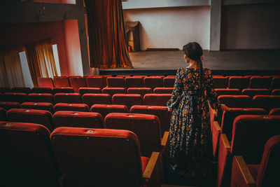 Rear view of woman standing by seats at theater
