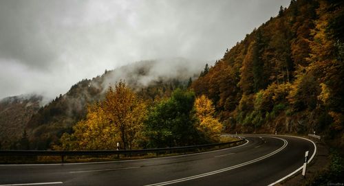 Road amidst trees against mountain range