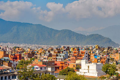 Aerial view of townscape by mountains against sky