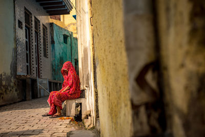 Woman in sari seating outside house