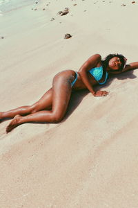 High angle view of young woman lying on sand