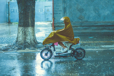 Side view of woman riding bicycle on wet street