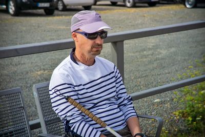 Midsection of man holding umbrella while sitting on railing