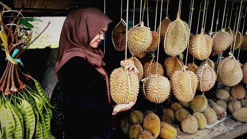 Smiling woman holding fruit at stall