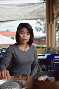 Woman opening container while sitting in restaurant