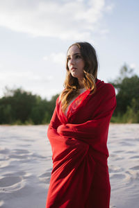 Portrait of a woman in a red cape on a sandy area