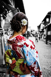 Rear view of woman wearing multi colored kimono standing on city street