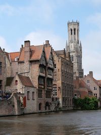 Buildings by river against sky