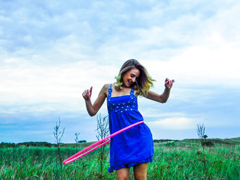Young woman standing on field against sky