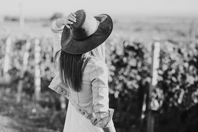 Side view of woman with hat standing against blurred background