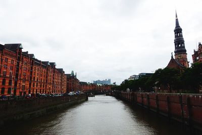 Canal amidst buildings in city against sky