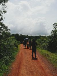 Rear view of man walking on road against sky