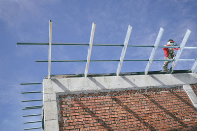 Low angle view of mason working at construction site against sky