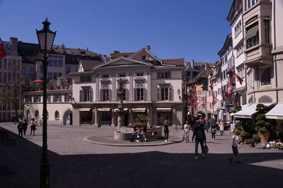People walking on street against buildings in city