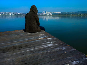 Rear view of pier over lake against sky