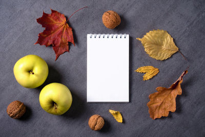 Autumn composition of dry leaves, apples and walnuts. white notepad with blank sheets for text