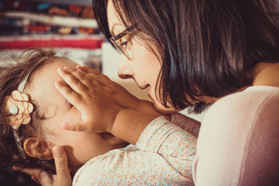 Close-up of mother playing with her small daughter at home.