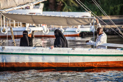 People sitting on sailboat in sea