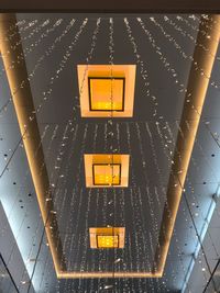 Low angle view of illuminated light hanging on ceiling in building