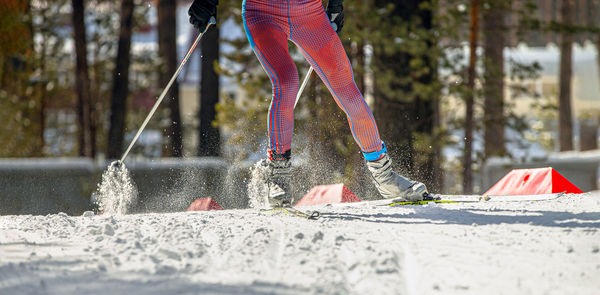 Legs skier athlete in splashes snow on track
