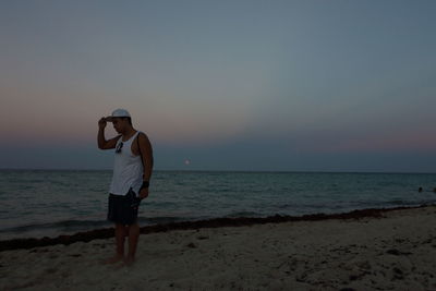 Full length of man standing on beach against clear sky