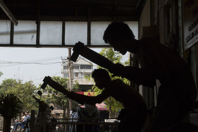 Side view of silhouette men working at workshop