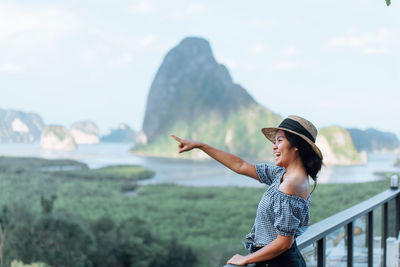 Woman pointing while standing against mountains