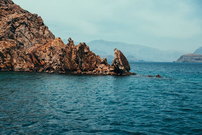 Rock formation in sea against sky